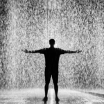 Seen Any Rain Yet, title image of a person standing with arms outstretched in the pouring rain